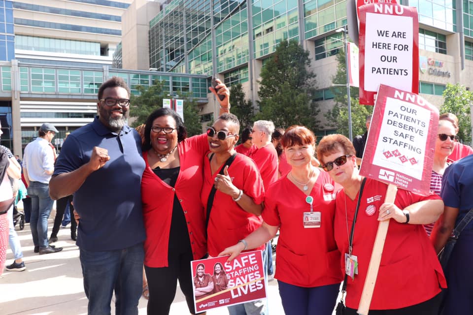 Nurses holding picket signs during a strike demonstration outside a healthcare facility / Author: Unknown, Public domain via Wikimedia Commons