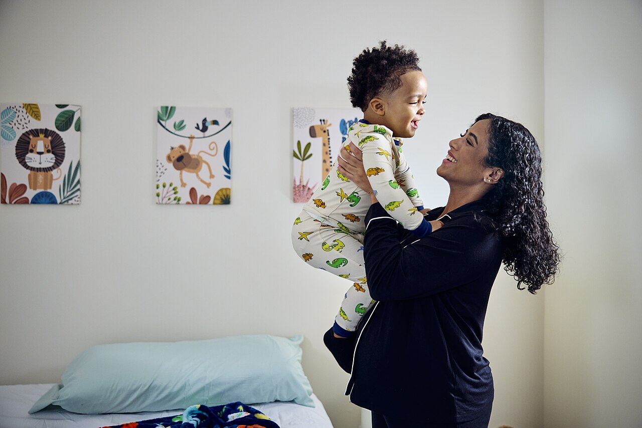 Mother holding young child in bedroom home setting / U.S. Department of Agriculture (USDA), Public Domain