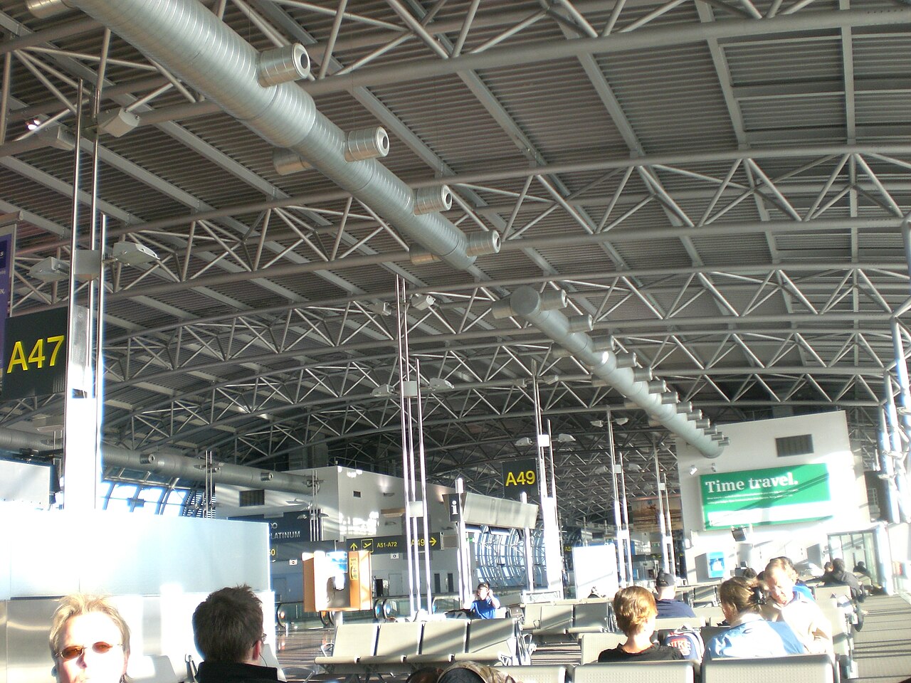 Brussels Airport Pier A waiting area with seating and gates / Wikimedia Commons - File:Brussels Airport Pier A.JPG