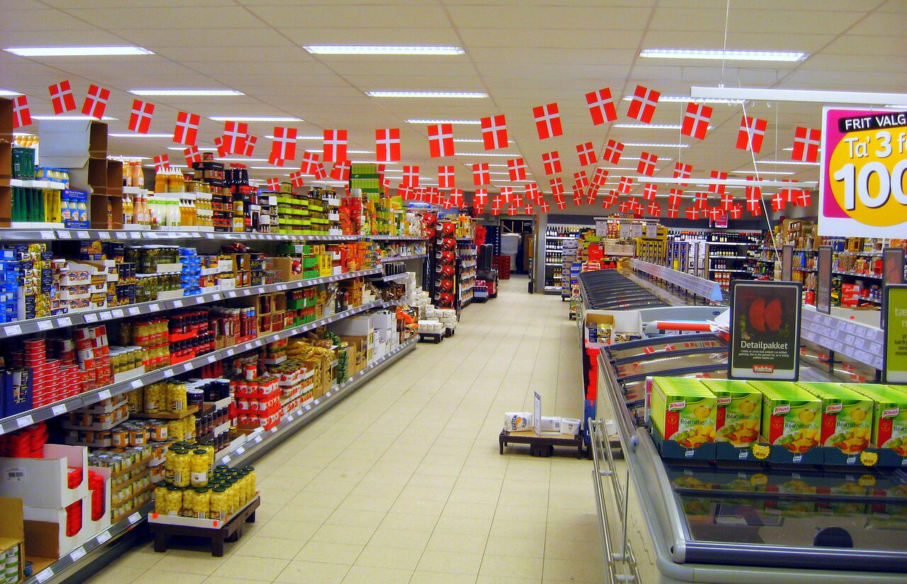 A supermarket storefront with flags, exterior view / Supermarket_z_flagami_(ubt).JPG: Ubt, CC BY-SA 3.0
