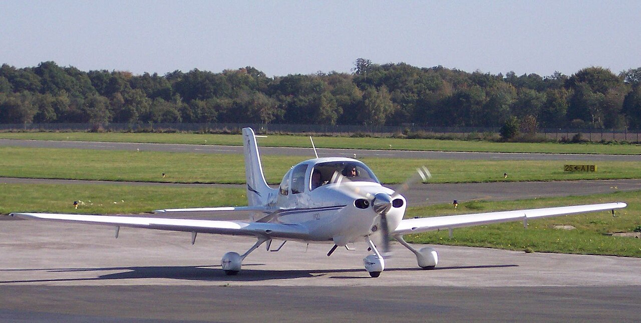 Side profile view of a white Cirrus SR20 single-engine piston aircraft on an airfield / Wikimedia Commons contributor