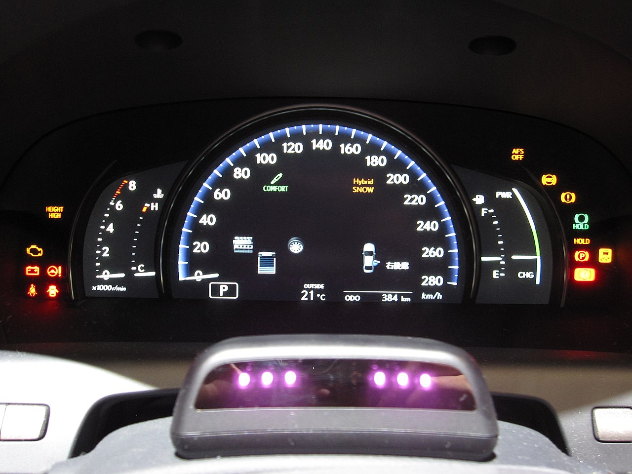 Lexus vehicle dashboard showing the LCD instrument panel alongside an integrated driver monitoring camera system mounted near the steering column / Wikimedia Commons