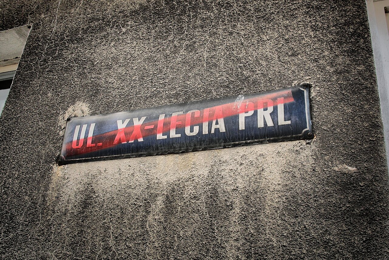 Crossed-out street name plaque reading "20th anniversary of Polish People's Republic," symbolizing the fall of communism in Poland / Wikimedia Commons / PRL tabliczka.JPG