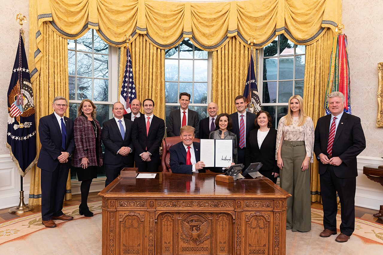 President Donald J. Trump at a desk signing a document, flanked by Ivanka Trump and Chris Liddell in the Oval Office / Official White House Photo by Joyce N. Boghosian