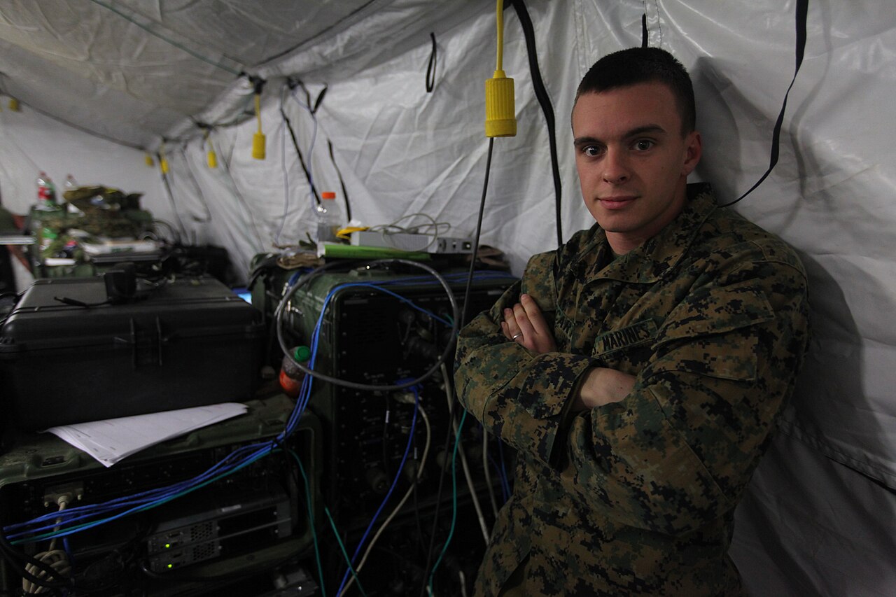 Sgt. Casey McCarthy, a Marine Corps data network specialist, poses by a wall of servers during a Realistic Urban Training exercise in 2012 / U.S. Marine Corps photo