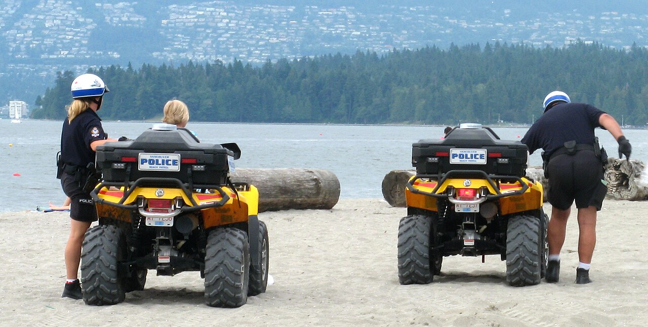 Uniformed Vancouver police officers walking on a sandy beach during a daytime patrol / Vancouver Police Department